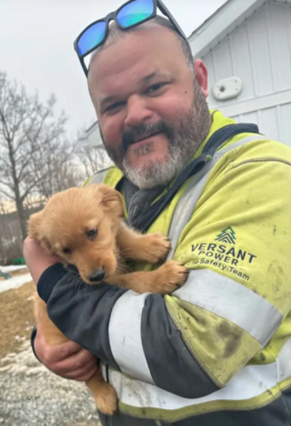 Man holding a small tan puppy outdoors by IBEW 1837