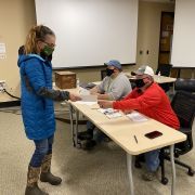 Woman handing a paper to seated volunteers at a table by IBEW 1837