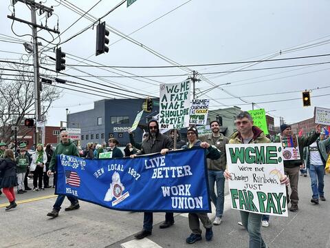 Protesters carrying WGME and IBEW 1837 signs in a parade march by IBEW 1837
