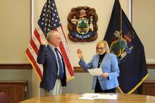 Woman being sworn in beside a man at a table by IBEW 1837