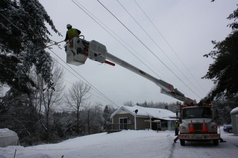 Utility worker in bucket truck trimming lines in snow by IBEW 1837
