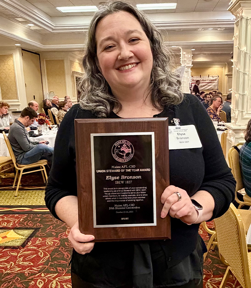 Woman holding a union steward award plaque at an event by IBEW 1837