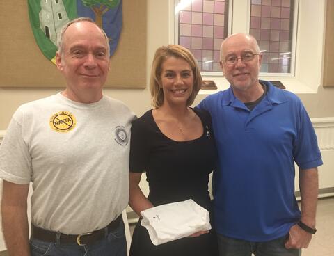 Three people posing indoors with a wrapped item by IBEW 1837