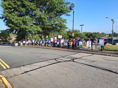 Picket line of workers holding signs along the sidewalk by IBEW 1837