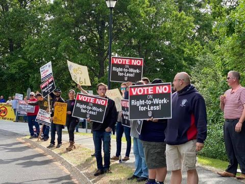 Protesters holding Vote No signs along a roadside by IBEW 1837