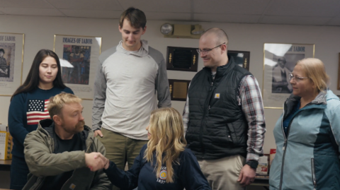 Five people in a room shaking hands and talking by IBEW 1837