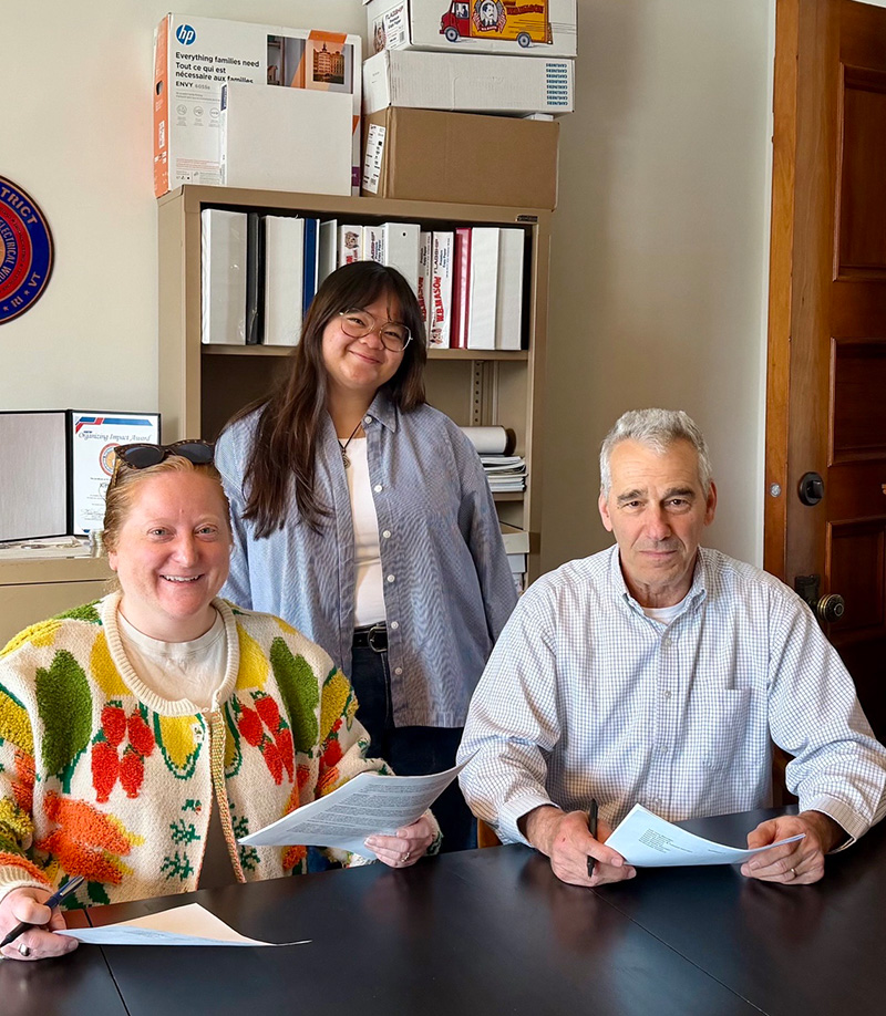 Three people signing papers in an office by IBEW 1837