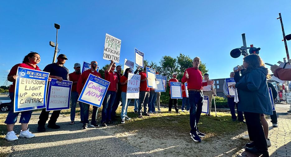 IBEW Local 1837 members holding protest signs outdoors by IBEW 1837